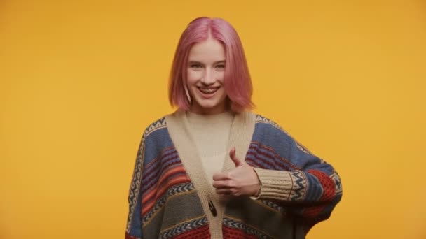 黄色い背景のジェスチャーのようなピンクの髪の女性 サインアップする学生 — ストック動画