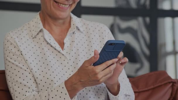 認識できない成熟した女性 スマートフォンを使用して閉じる モバイル携帯電話のインドアでオンラインブラウジングシニア大人の教師 — ストック動画