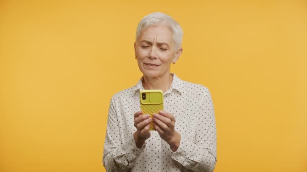 Mujer Mayor Escribiendo Mensaje Respuesta Fondo Amarillo Usando Smartphone — Vídeos de Stock