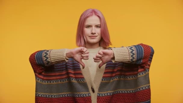 黄色い背景に嫌なジェスチャーを表示する学生 ピンクの髪の若い女性の親指のサイン — ストック動画