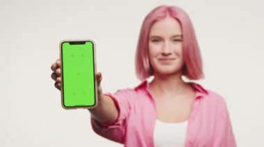 Beyaz Arkaplanda Yeşil Ekran Akıllı Telefonu Gösteren Kadın, Bulanık Pembe Saçlı Genç Kadın Başıyla Krom Anahtarlı Akıllı Telefonu Tutuyor
