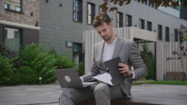 İş adamı okuma raporu dışarıda dizüstü bilgisayarda çalışıyor, adam dışarıda bilgisayar kullanıyor.