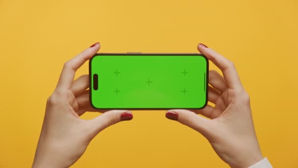黄色背景下的水平绿色屏幕智能手机Pov 女性手持带有标记的彩色密钥智能手机近视放大 — 图库视频影像