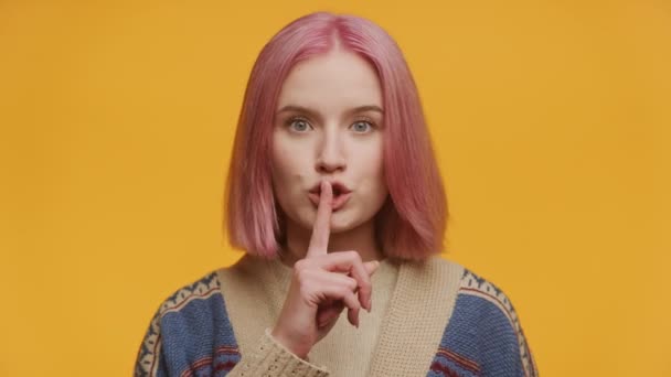 イエローバックグラウンドで沈黙を示す学生 ピンクの髪の女性 Shhh サイン 閉じる — ストック動画