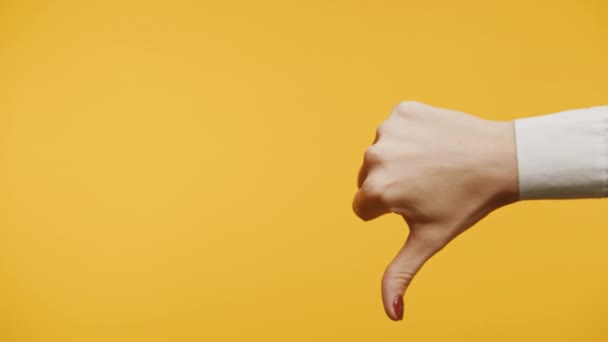 親指の下のジェスチャー 黄色い背景に閉じる 女性手の嫌な印 — ストック動画