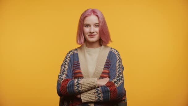 イエローバックグラウンドでブレースの肖像画を持つ自信のあるピンクの髪の学生 カメラと笑顔を見ている若い女性 — ストック動画