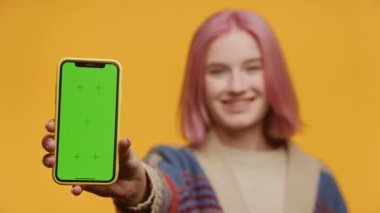 Sarı Arkaplanda Yeşil Ekran Akıllı Telefonu Tutan Kadın, Dikey Krom Anahtarı Gösteren Pembe Saçlı Genç Bayan Akıllı Telefon ve Gülümseyen Rafta Odaklanma