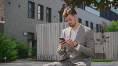 Şehir merkezindeki açık havada akıllı telefon kullanarak iş adamı internette geziniyor.