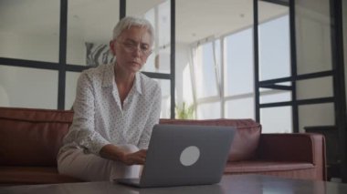 Orta yaşlı kadın laptopta kötü haberleri okuyor, yetişkin kadının başı dertte.