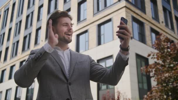 スマートフォンアウトドアを使用してビデオ通話でビジネスマン挨拶ジェスチャー — ストック動画