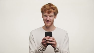 Kızıl Saçlı Adam Beyaz Arkaplanda Mesajlaşmadan Önce Düşünüyor, Kızıl Adam Akıllı Telefon kullanarak Mesajı Okuyor