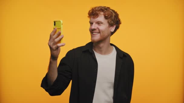Redhead Man Falando Chamada Vídeo Usando Smartphone Fundo Amarelo — Vídeo de Stock