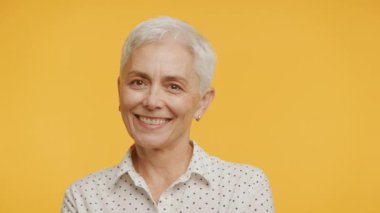 Gri Saçlı Olgun Kadın Sarı Arkaplanda Kameraya Bakıyor