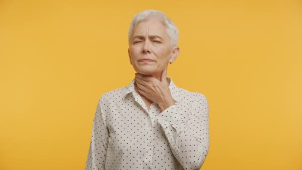 Mujer Mayor Sintiéndose Enferma Eleva Garganta Sobre Fondo Amarillo — Vídeos de Stock