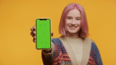 Sarı Arkaplanda Yeşil Ekran Akıllı Telefonu Gösteren Pembe Saçlı Kadın, Dikey Krom Anahtarlı Akıllı Telefonu Tutan Genç Kadın