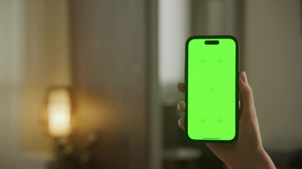 左手边有复制空间的垂直绿色屏幕智能手机 公寓中的女性手持彩色密钥智能手机 — 图库视频影像