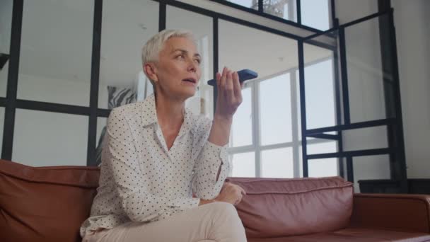Idősebb Kanapén Használ Hangfelismerő Telefonján Egy Modern Otthon — Stock videók