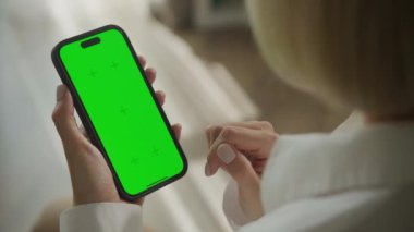 Yeşil ekranlı akıllı telefon kullanan bir kadının elinin yakın çekimi, uygulama veya mobil web sitesi modellemeleri için idealdir