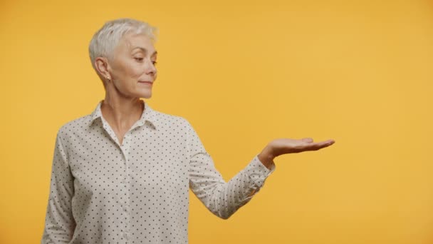 Старша Жінка Теплою Посмішкою Жестикулюючи Рукою Яскравому Жовтому Тлі — стокове відео