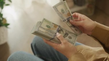 Omzunun üstünden bakılan bir yığın Amerikan doları sayan kişi.