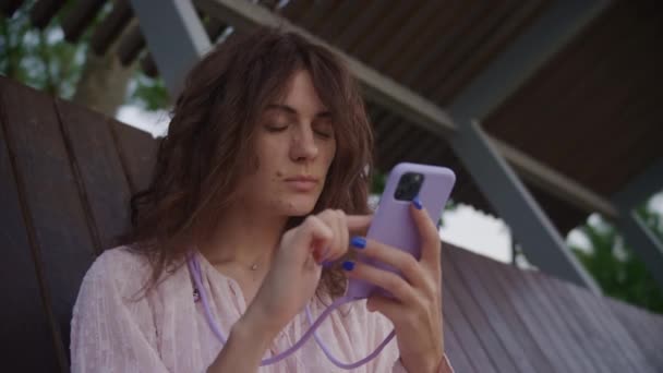 紫色の携帯電話とマッチングのネイルポリッシュがメッセージを読むことで吸収される熟考の女性 — ストック動画