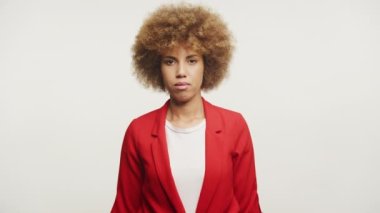 Afro saçlı, kırmızı ceketli, kollarını kavuşturmuş, gülümseyen bir kadın.