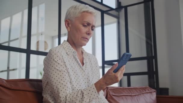 Starsza Kobieta Krótkimi Siwymi Włosami Wygląda Problematycznie Czytając Sms Swoim — Wideo stockowe