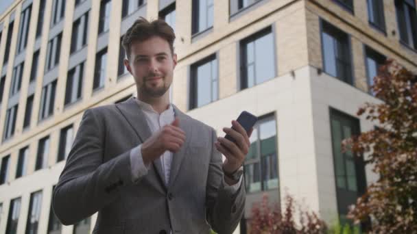 带着智能手机在户外竖起大拇指微笑的男人 — 图库视频影像