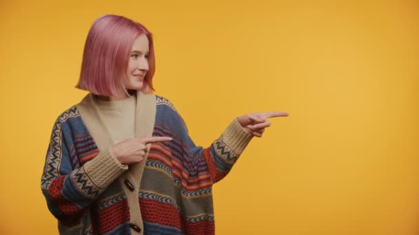 彼女の側を指すピンクの髪の笑顔の女性 パターンセーターを着用 — ストック動画