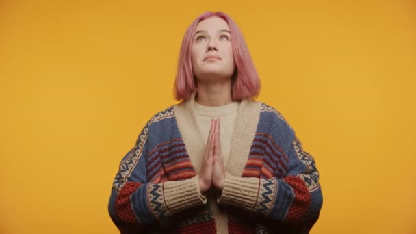 黄色の背景に対する祈りの位置で上向きにピンクの髪を持つセリーン若い女性 — ストック動画
