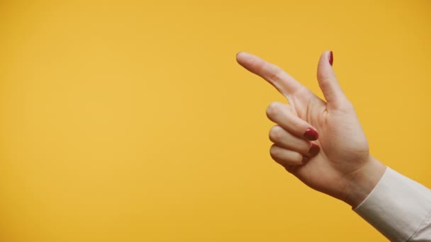 鮮やかな黄色の背景にポインティングジェスチャーを作る赤いマニキュアで手を挙げる — ストック動画