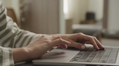 Modern çalışma ve bağlantıya odaklanmış bir dizüstü bilgisayarın üzerinde gezinen ellerin detaylı görüntüsü.