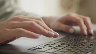 Modern bir dizüstü bilgisayar klavyesinde manikürlü tırnakları olan zarif kadın ellerinin yakın çekimi.