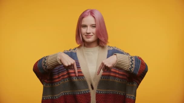 Confident Girl Pink Hair Pointing Vibrant Sweater Yellow Background — Stock Video