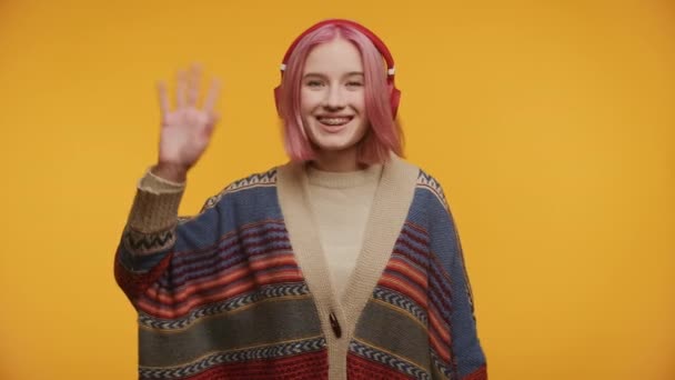 Radostný Dospívající Růžovými Vlasy Červenými Sluchátky Mává Ahoj Oblečený Barevném — Stock video