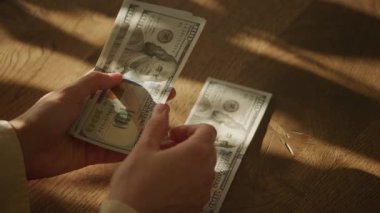 Tahta bir yüzey üzerinde Amerikan dolarlarını sayan bir kişi.
