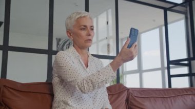 Ofiste cep telefonu kullanan kısa saçlı yaşlı bir bayan.