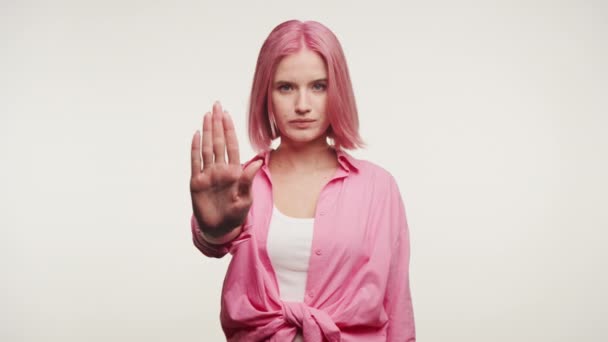 ピンクの髪を持つ若い女性は 停止手のサインを示し 白い背景に境界線を伝えます — ストック動画