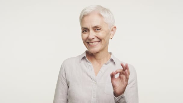 Lächelnde Ältere Frau Mit Silbernem Haar Macht Ein Zeichen Das — Stockvideo