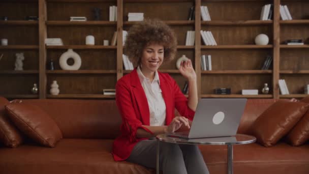 ラップトップ上のビデオ通話中にカーリーヘアを振っているフレンドリーな起業家 — ストック動画