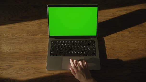 在木制桌子上与带有绿色屏幕的笔记本电脑进行交互 — 图库视频影像