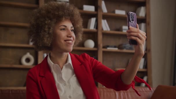 Kırmızı Ceketli Gülümseyen Bir Kadın Telefonuyla Video Görüşmesi Yapıyor — Stok video