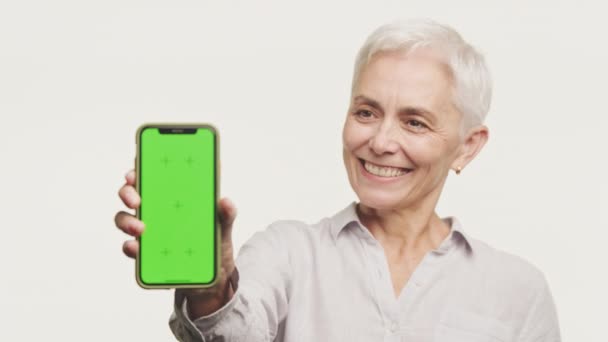 Starší Žena Usmívá Ukazuje Telefon Zelenou Obrazovkou Ideální Pro Prezentaci — Stock video