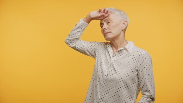 Mujer Anciana Cansada Sosteniendo Frente Sobre Vibrante Fondo Amarillo — Vídeo de stock