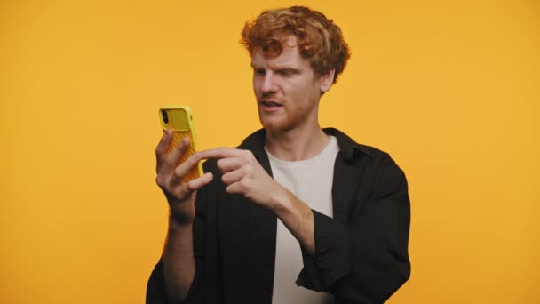 Missnöjd Ung Man Tittar Smartphone Mot Levande Gul Bakgrund — Stockvideo