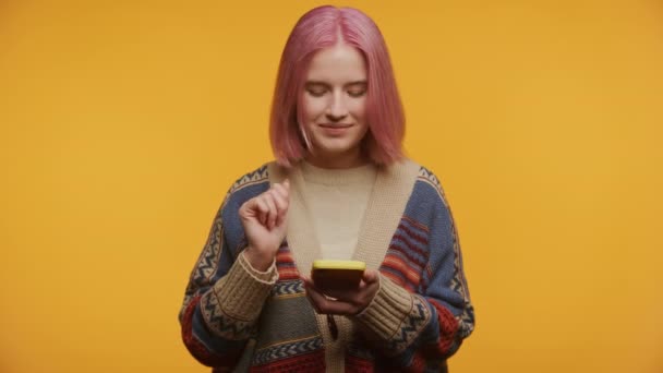 Σκεπτική Γυναίκα Ροζ Μαλλιά Κοιτάζοντας Τηλέφωνο Κίτρινο Φόντο — Αρχείο Βίντεο