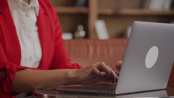 Skoncentrowana Kobieta Kręconymi Włosami Czerwonym Garniturze Pomocą Laptopa Przy Biurku — Wideo stockowe