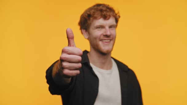 一个满头乱蓬蓬的红头发的男人在欢乐的黄色背景面前竖起大拇指 微笑着 — 图库视频影像