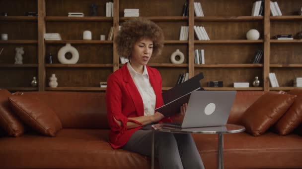 Engaged Businesswoman Przeglądanie Dokumentów Podczas Rozmowy Wideo Przy Użyciu Laptopa — Wideo stockowe