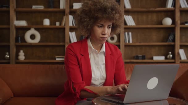 Kobieta Kręconymi Włosami Wyglądająca Zestresowaną Podczas Korzystania Laptopa Siedząca Skórzanej — Wideo stockowe